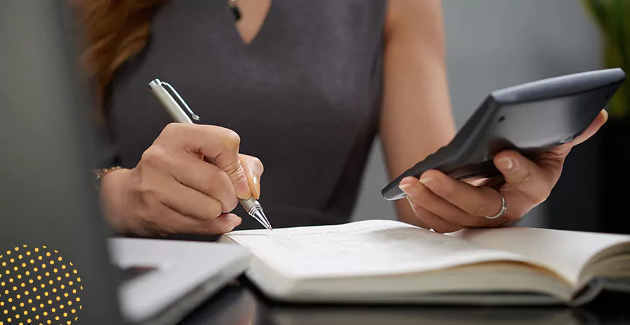 imagem de uma mulher segurando uma calculadora e anotando com uma caneta em um caderno representando como calcular décimo terceiro proporcional