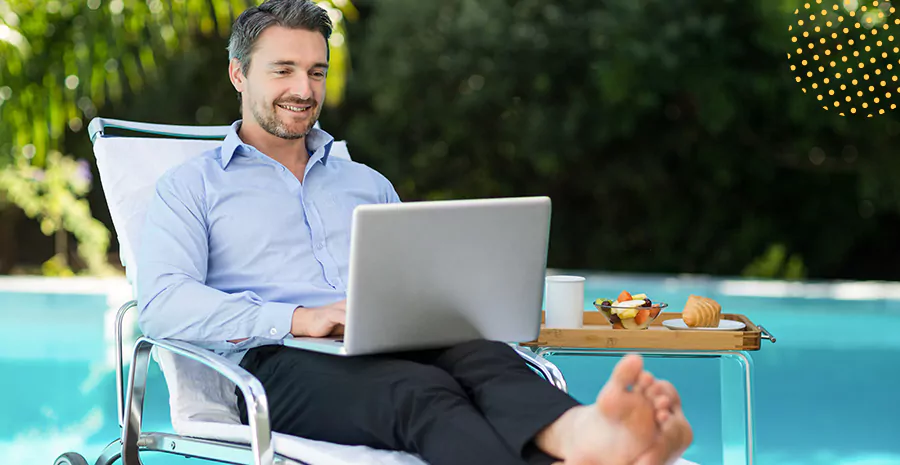 Imagem de um homem mezendo no computador em uma cadeira de piscina