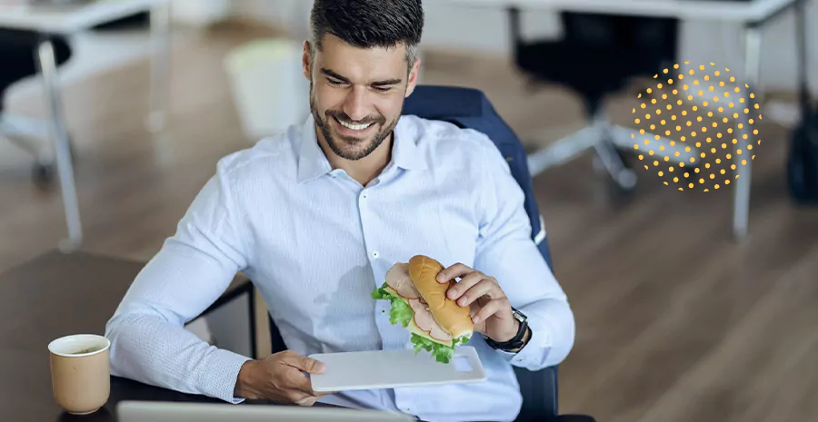 imagem de um homem sorrindo sentado segurando um sanduíche, representando o auxílio alimentação