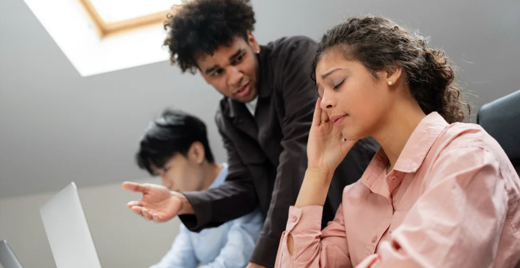 Mulher com semblante cansado enquanto homem conversa