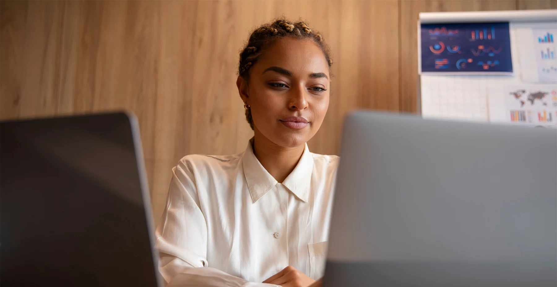 Uma mulher sentada em uma mesa com seu laptop