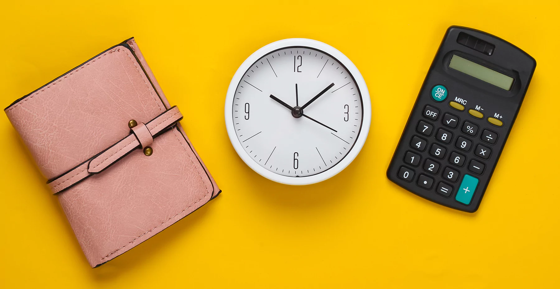 Carteira rosa de couro, um relógio de ponteiro branco e uma calculadora preta em um fundo amarelo