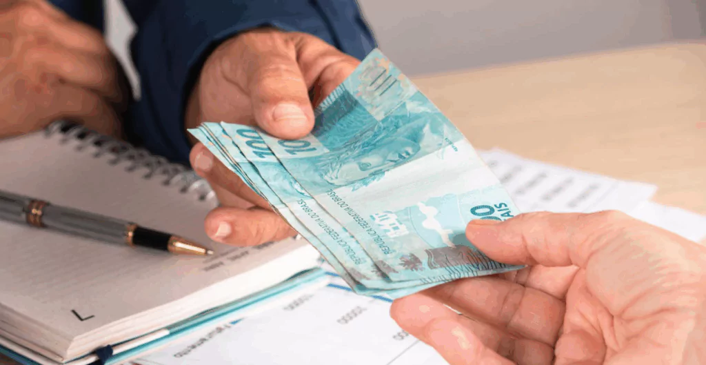 Imagem de uma transação financeira onde uma pessoa entrega uma nota de 100 reais para outra, simbolizando pagamento ou troca de dinheiro.